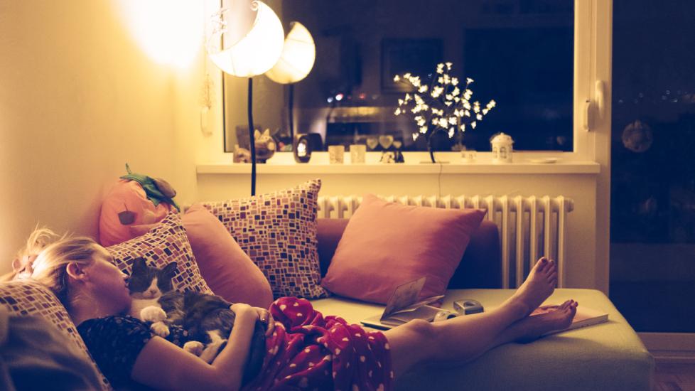 how to keep cat calm during fireworks-woman cuddling with cat with fireworks anxiety on coouch.